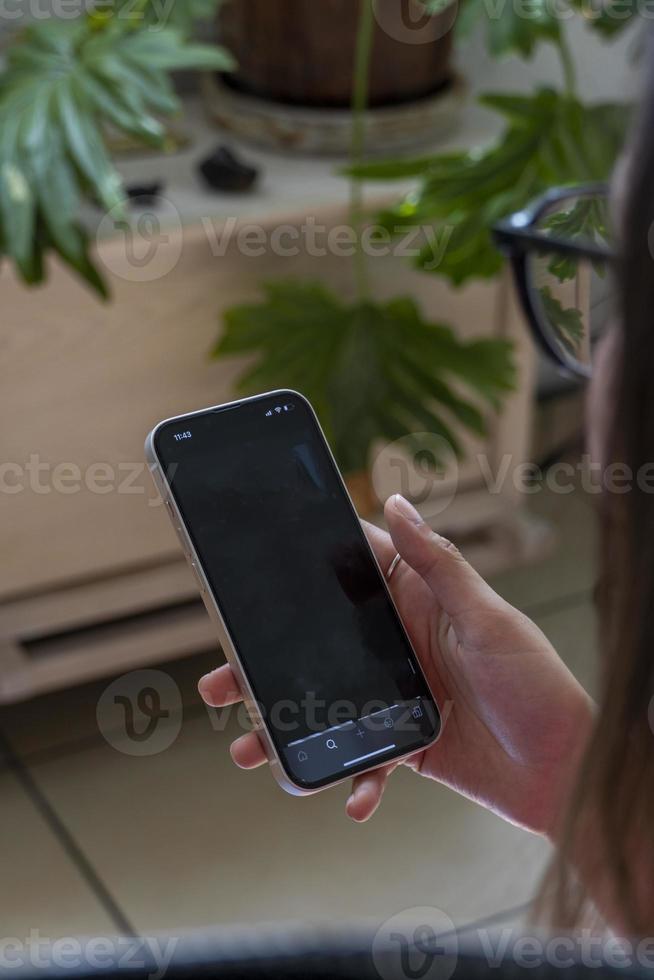 young hispanic woman, looking at her cell phone checking her social networks photo