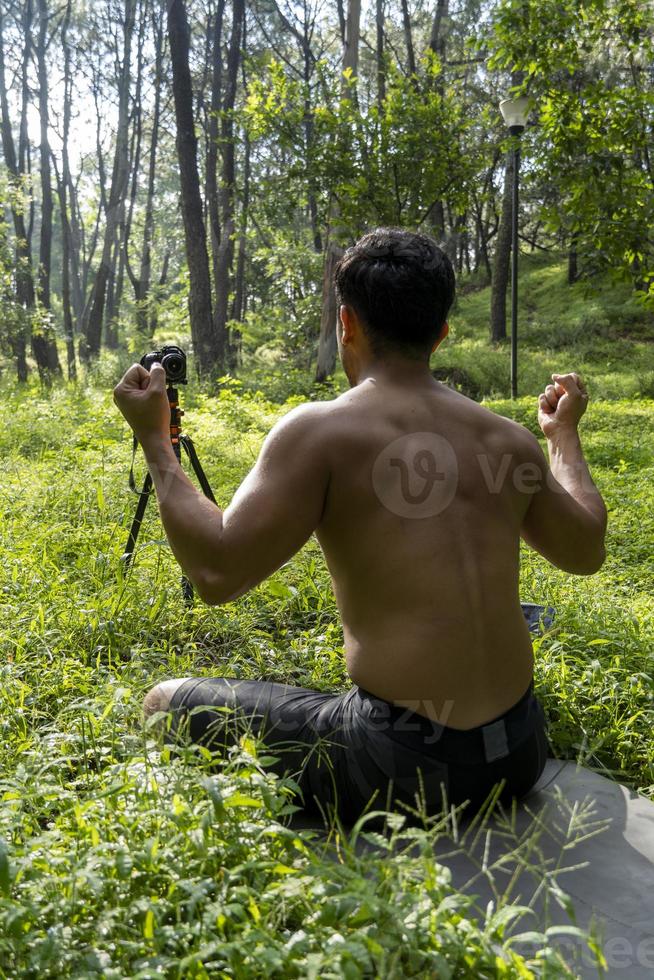 Millennial guy meditating with trainer online via tablet ipad connection, in the forest, broadcasting online your class and instructions, mexico photo