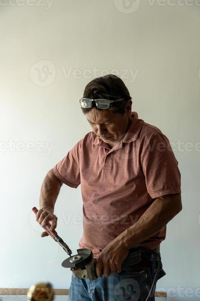 man using angle grinder, cutting a screw, friction sparks, clamping screw with tweezers concentration face and concern latino man photo