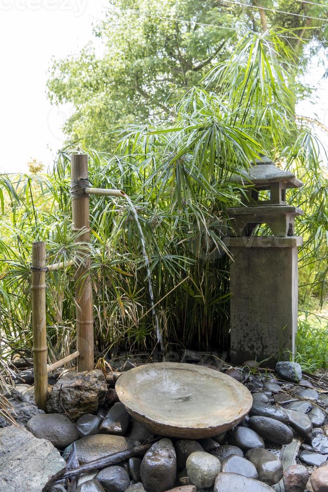 small asian fountain with bamboo, river stones, and falling water, in mexico photo