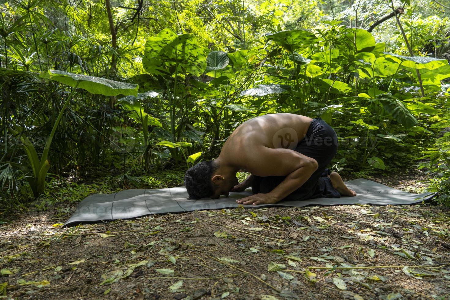 Young latin man arranging his yoga mat, inside a forest on a plain, direct contact with nature, mexico photo