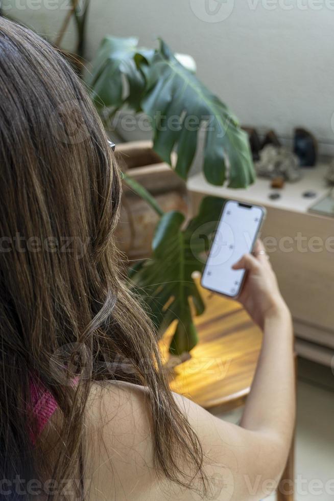 joven latina en su celular, diferentes actividades, pantalla blanca, maqueta o pantalla verde foto