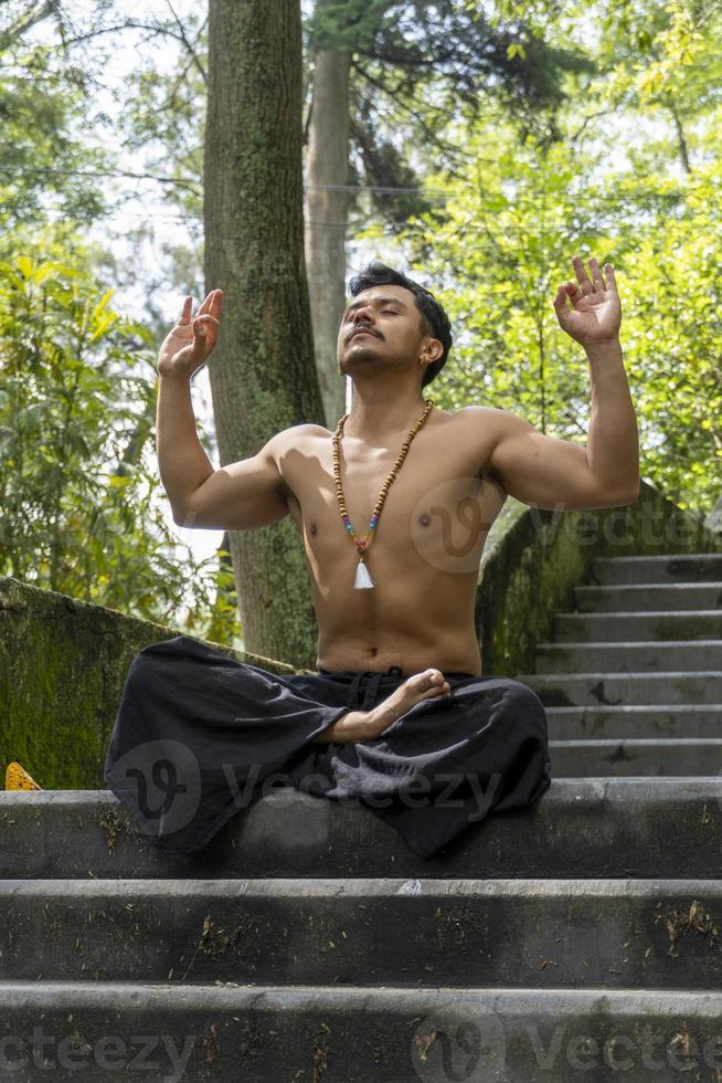 young man doing meditation on a stairway in a forest, mexico photo