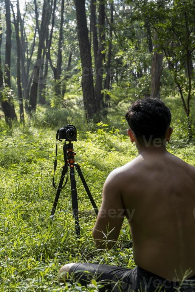 Millennial guy meditating with trainer online via tablet ipad connection, in the forest, broadcasting online your class and instructions, mexico photo
