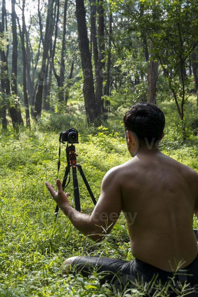 Millennial guy meditating with trainer online via tablet ipad connection, in the forest, broadcasting online your class and instructions, mexico photo