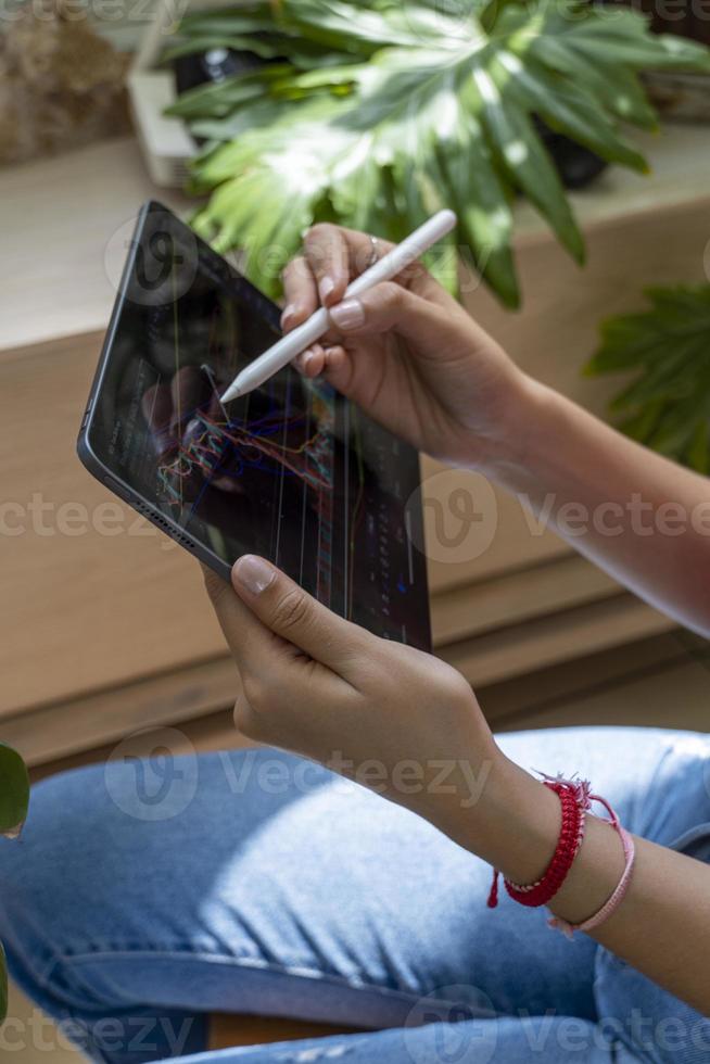 young woman, watching the stock market on her tablet, while drawing on the chart photo