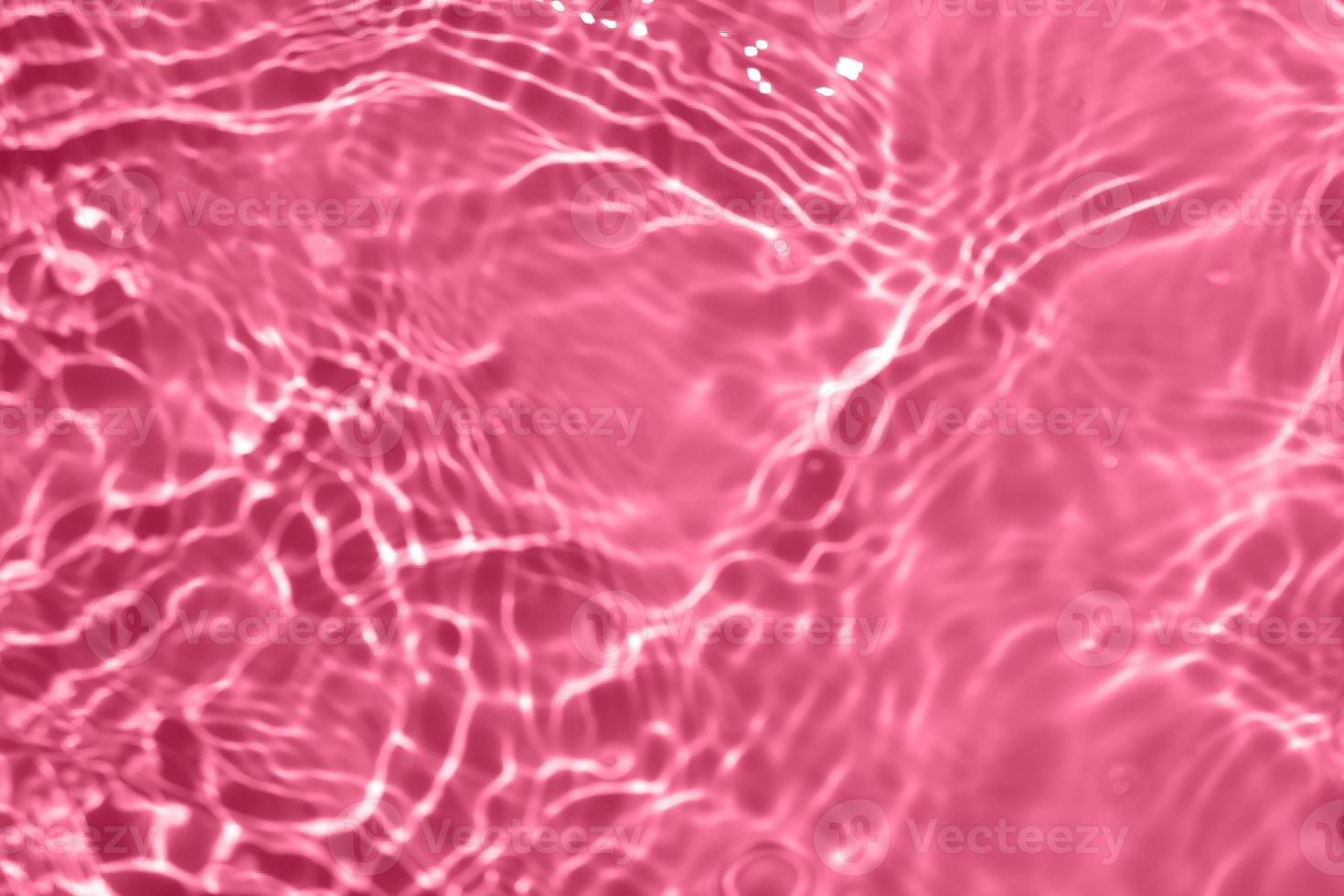 Defocus blurred transparent pink colored clear calm water surface texture with splash, bubble. Shining pink water ripple background. Surface of water in swimming pool. Pink bubble water shining. photo