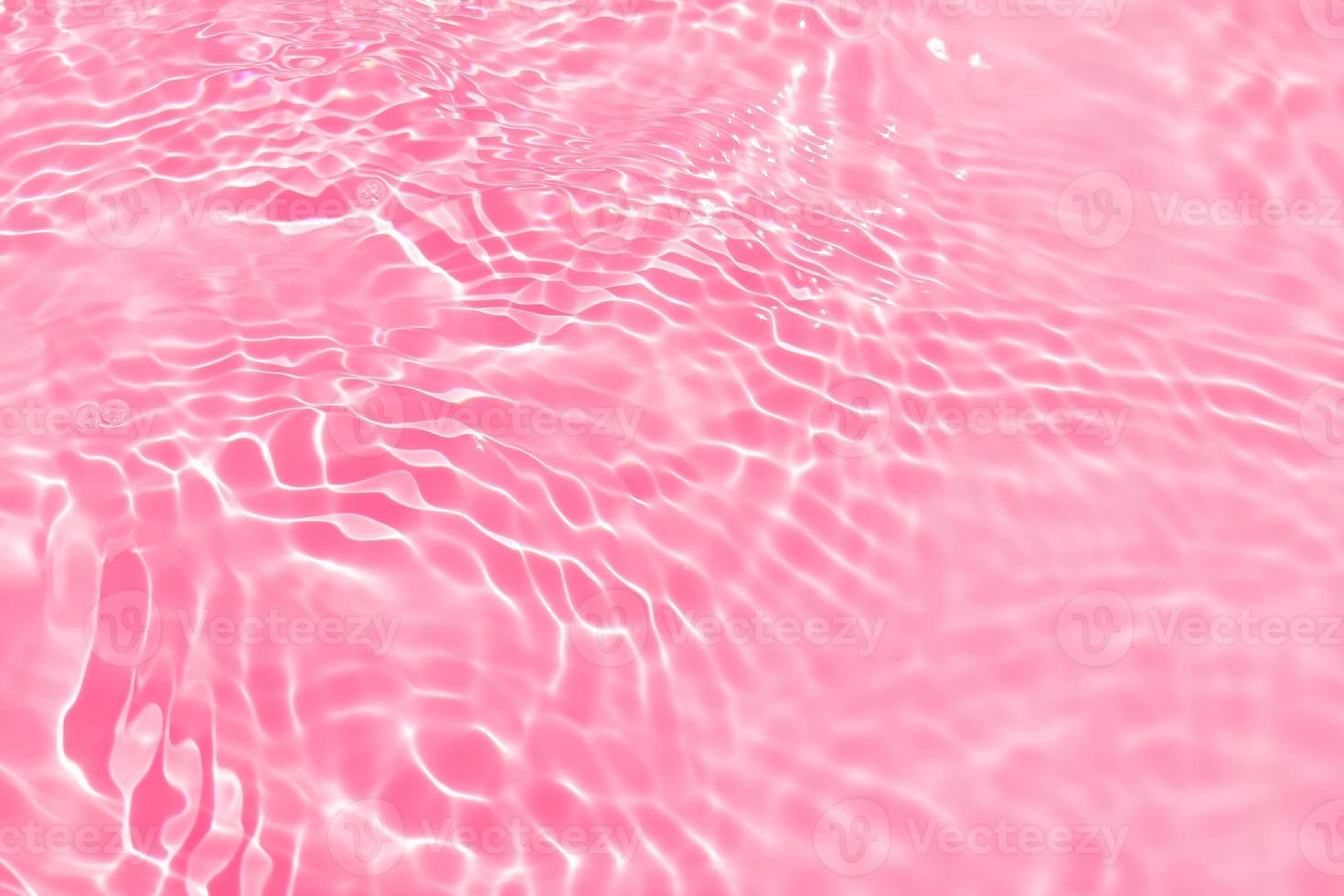 Defocus blurred transparent pink colored clear calm water surface texture with splash, bubble. Shining pink water ripple background. Surface of water in swimming pool. Pink bubble water shining. photo