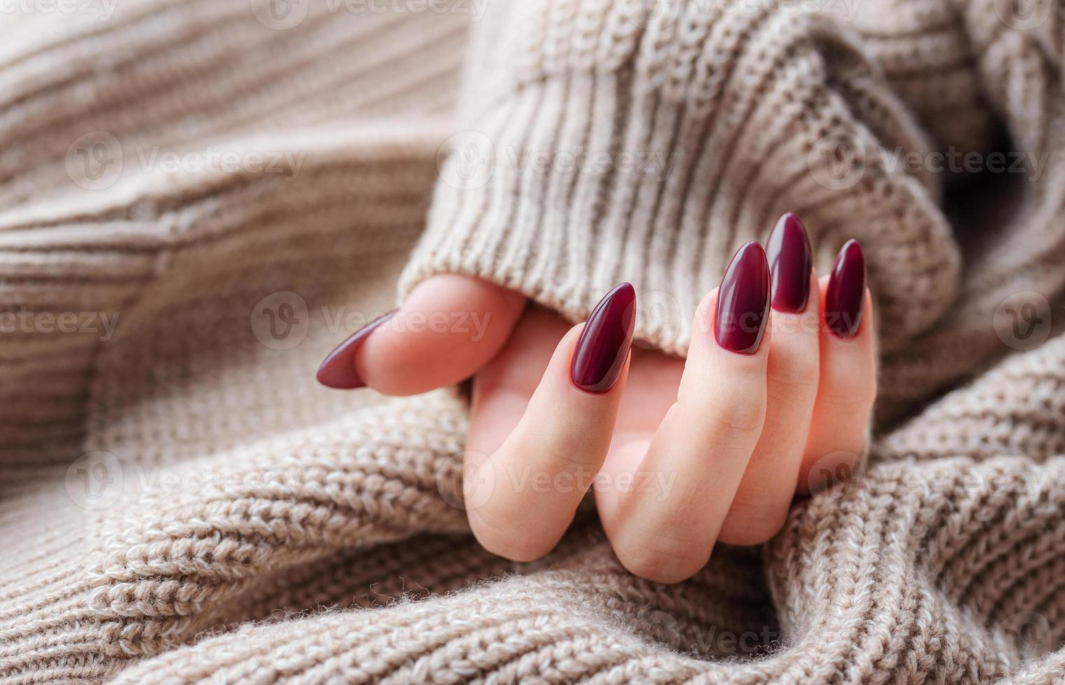 Hands of a young woman with dark red manicure on nails photo