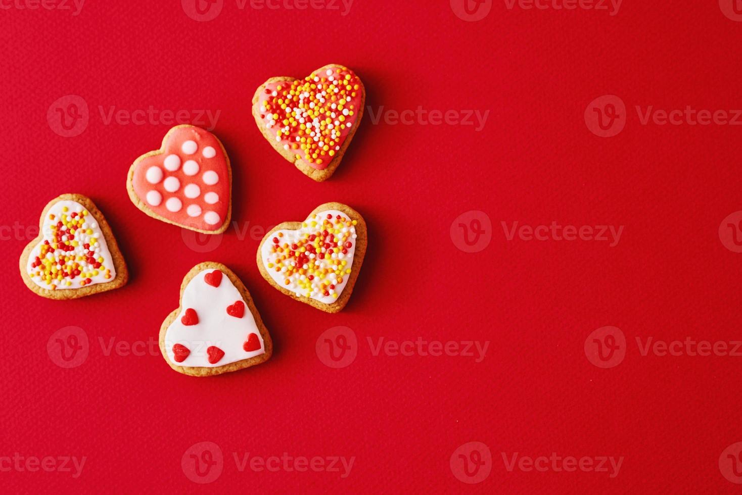 Decorated with icing and glazed heart shape cookies on the red background with copy space. Valentines Day food concept photo