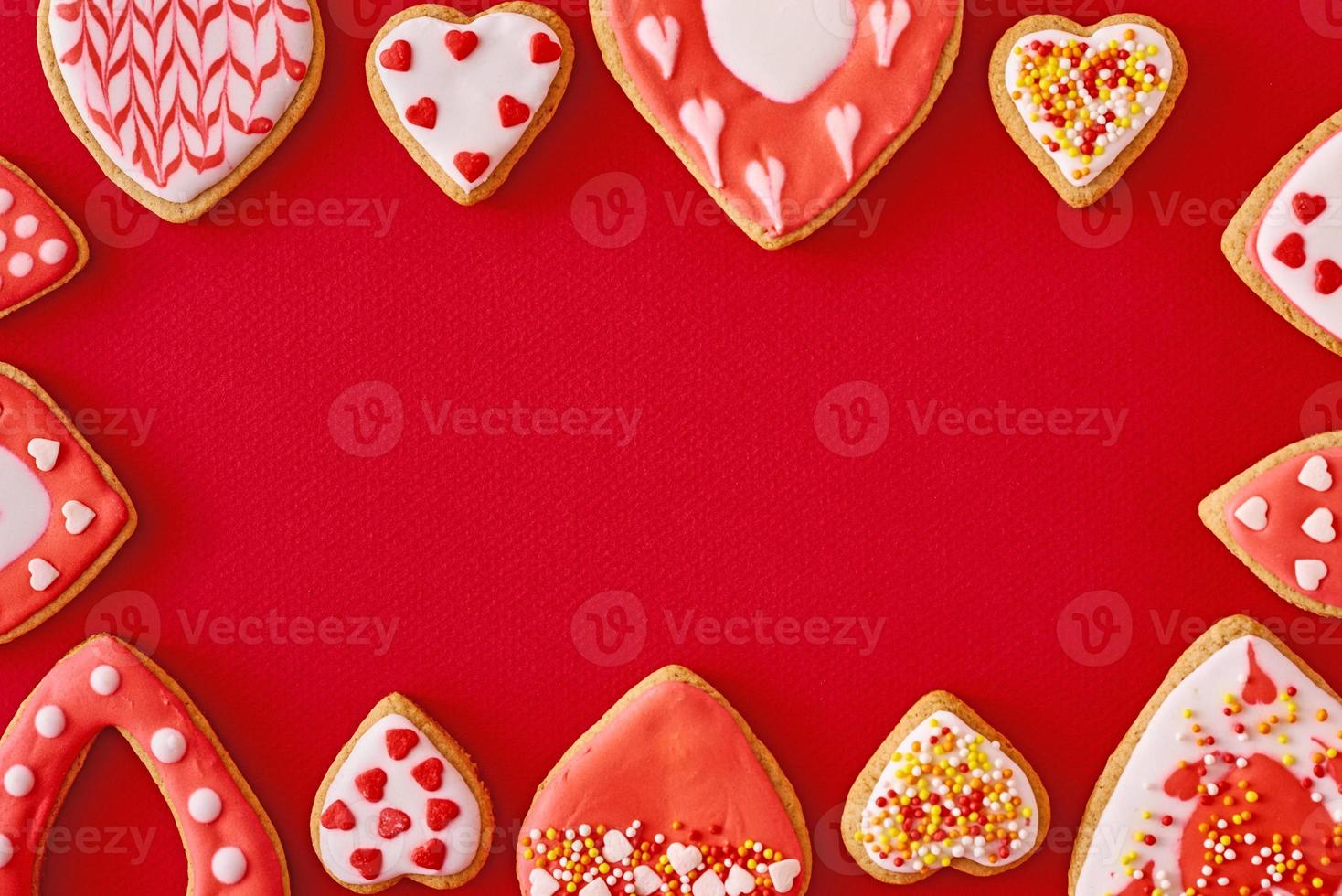 Frame with glazed and decorating heart shape cookies on the red background. Valentines Day food concept photo