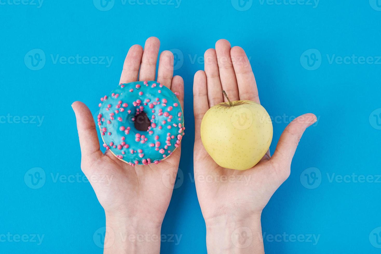 Woman choosing betwen apple and donut in her hands. Healthy food concept. photo