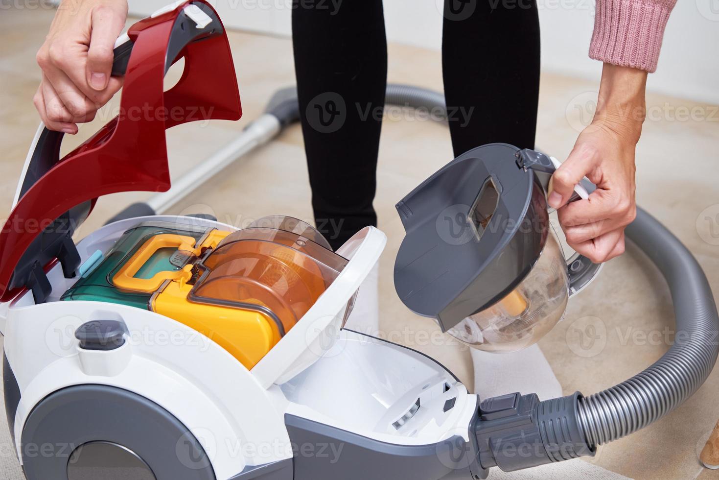 woman take out container of dust from vacuum cleaner photo