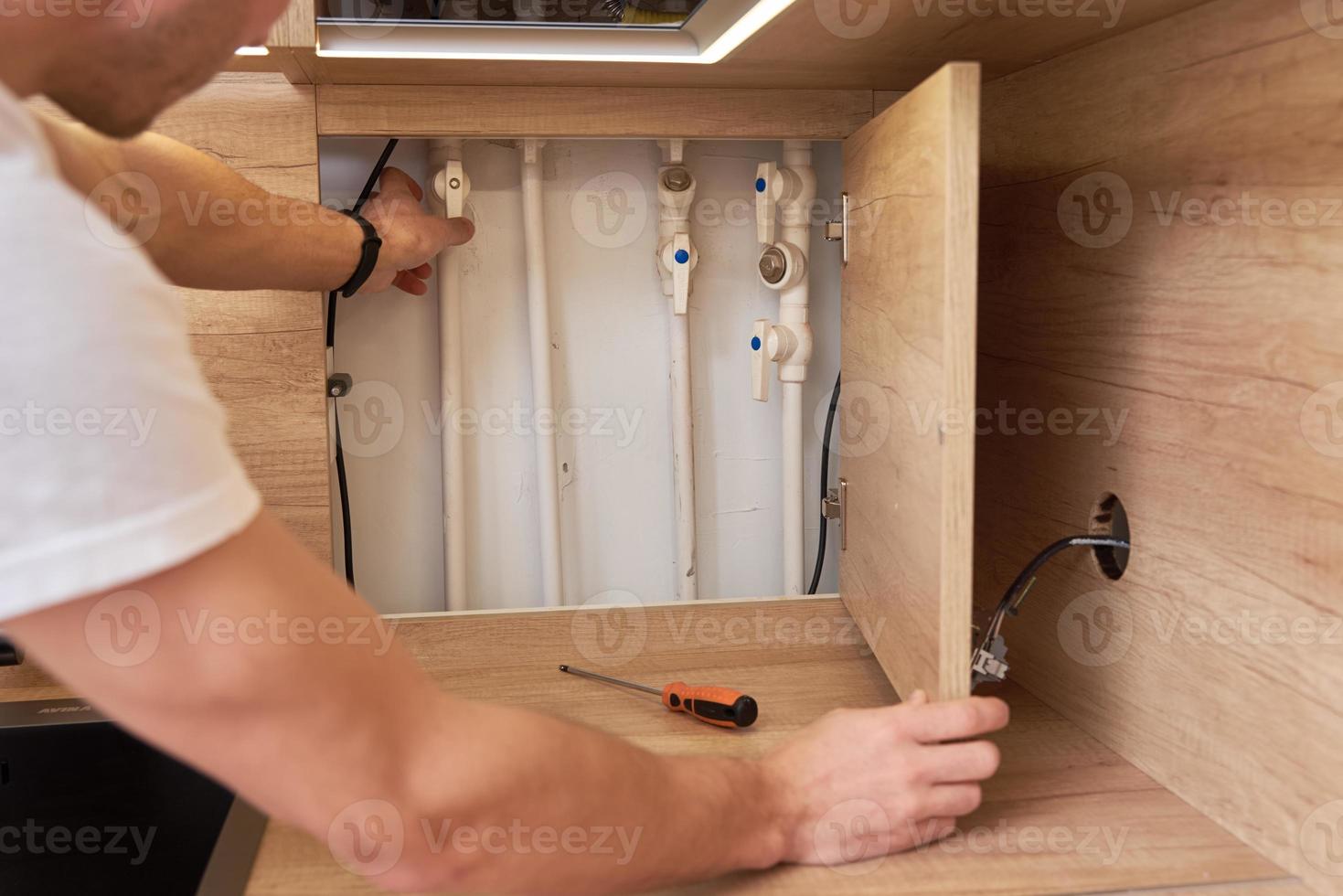 Man opens an assembly hatch and checks water pipes photo