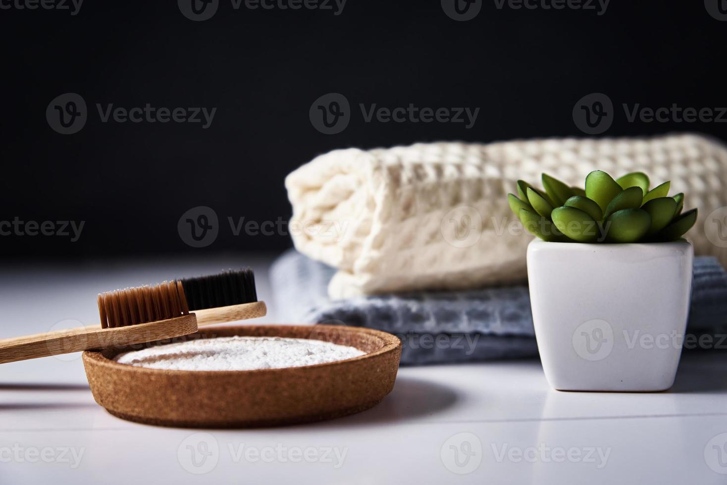 cepillos de dientes de bambú, bicarbonato de sodio y toallas de baño sobre fondo oscuro foto