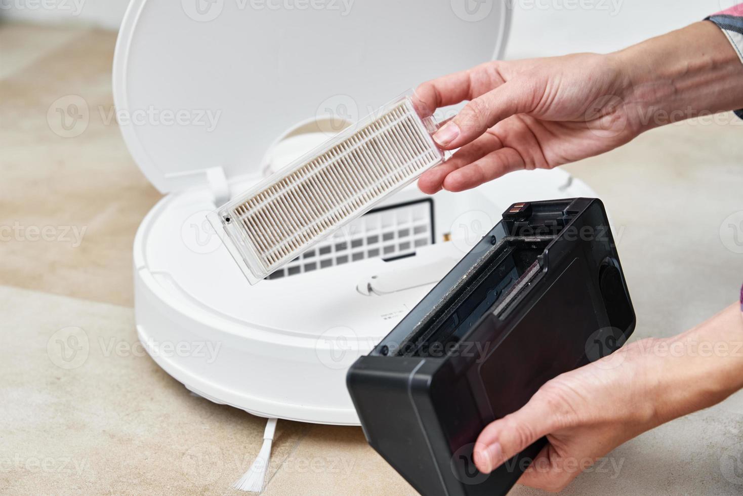 Woman cleans dust container in robotic vacuum cleaner. photo