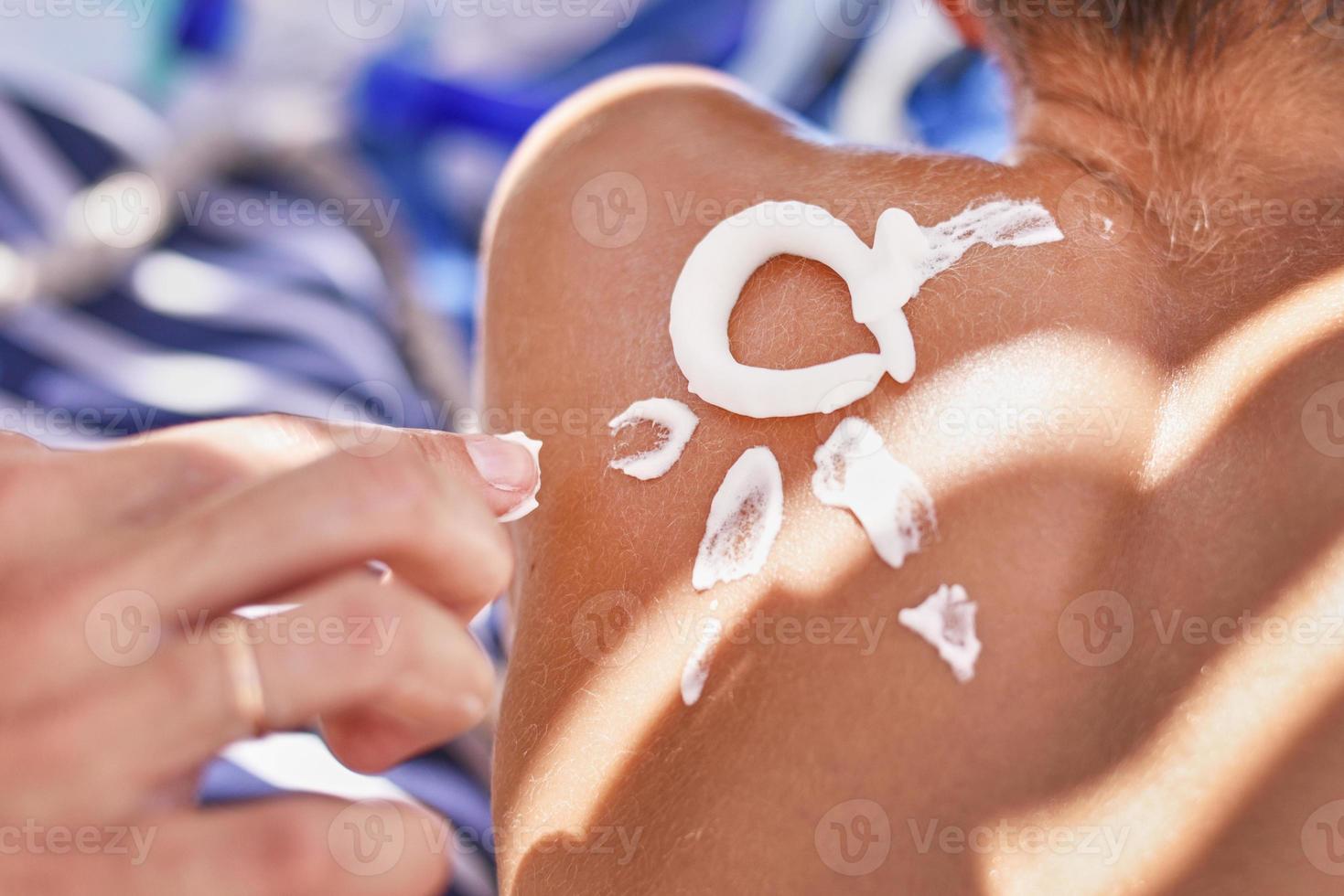 Woman apply protective sunscreen on the boy's shoulders skin photo