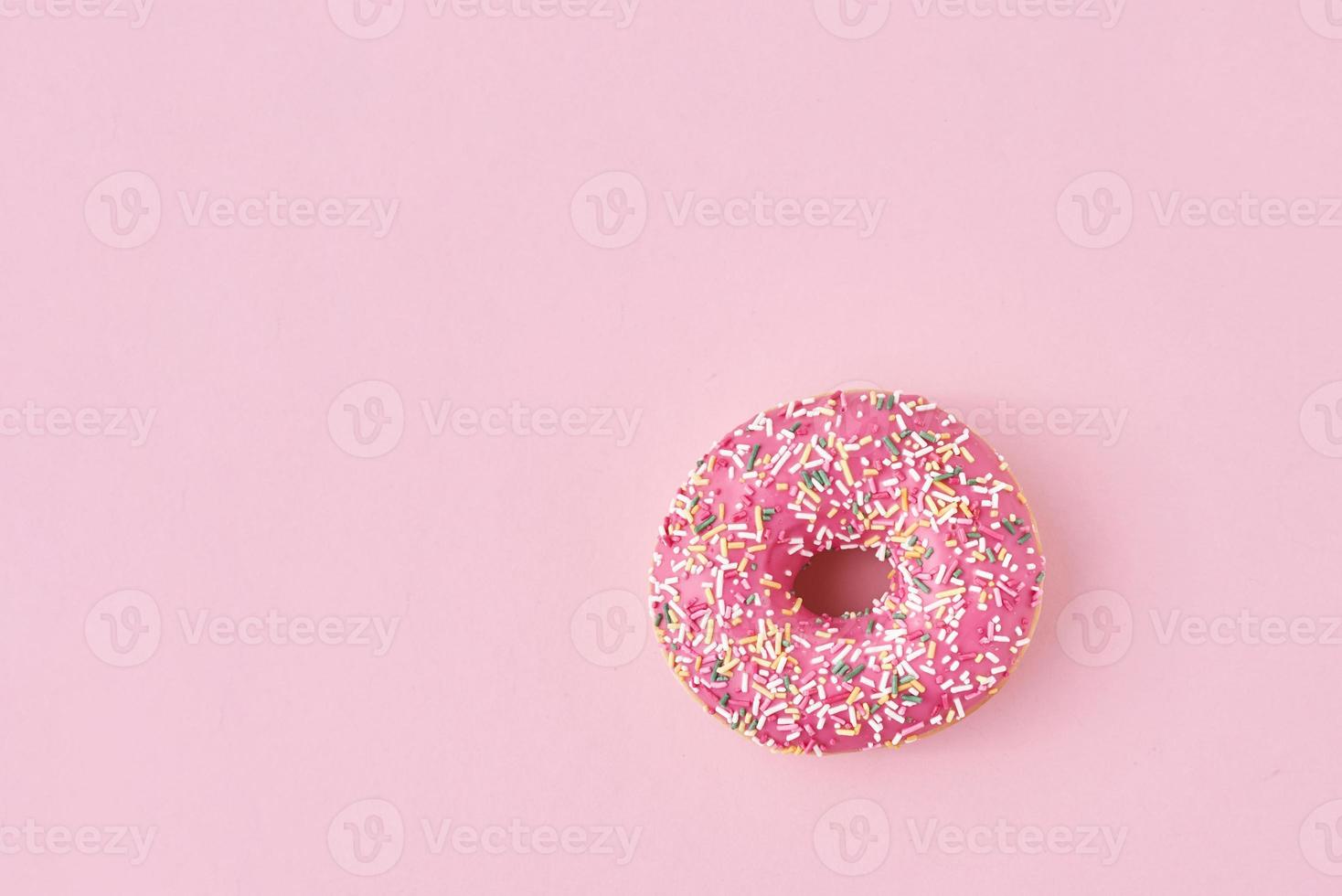 donats decorated sprinkles and icing on a pink background. Creative and minimalis food concept, top view flat lay photo