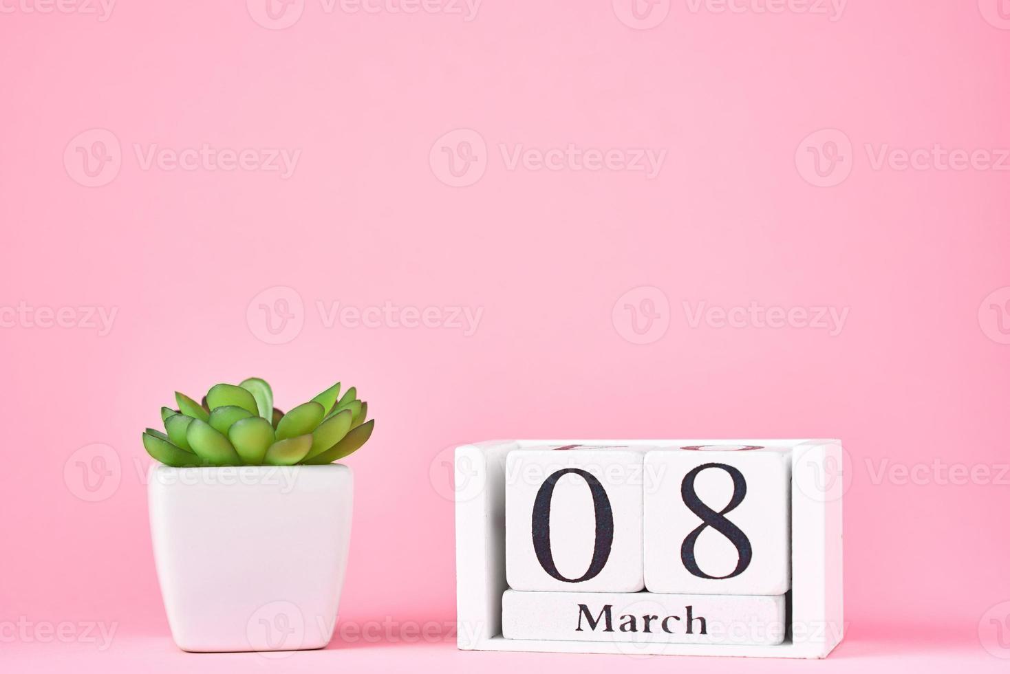Women's Day concept. Wooden calendar block with date 8 march and plant on the pink background with copy space photo