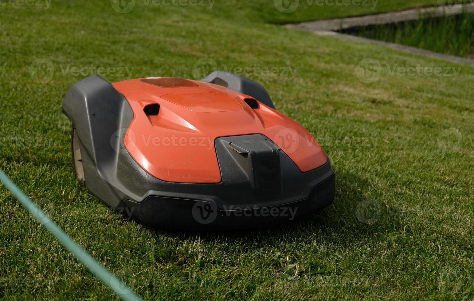 Robotic Lawn Mower on green grass background.Automatic robot lawnmower in modern garden.Green grass trimming with lawn mower. Close-up view of the lawn mower dirty blade after mowing the lawn. photo