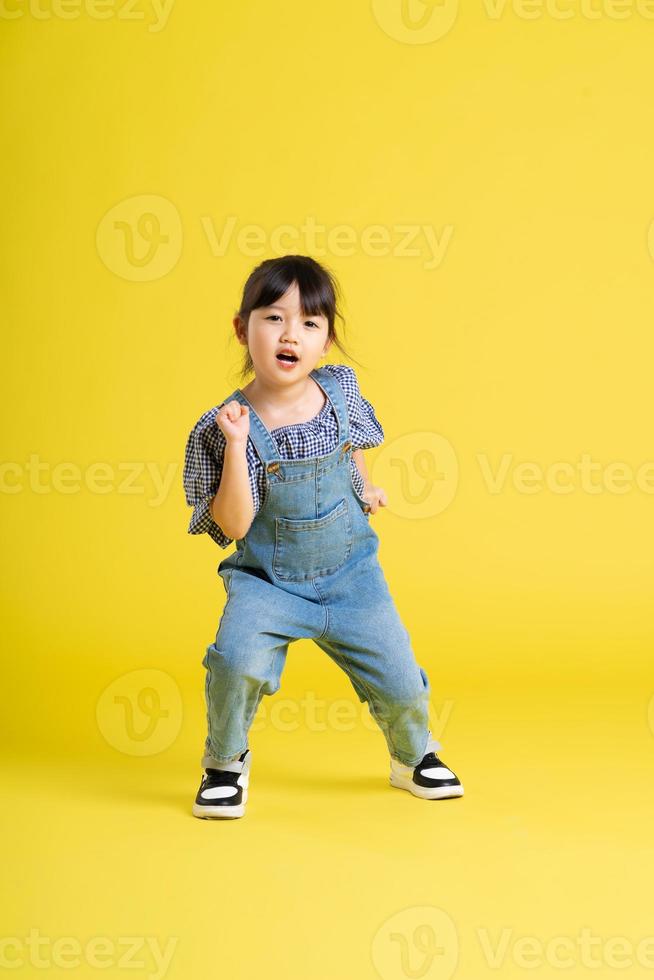 full body image of beautiful asian baby girl on yellow background photo