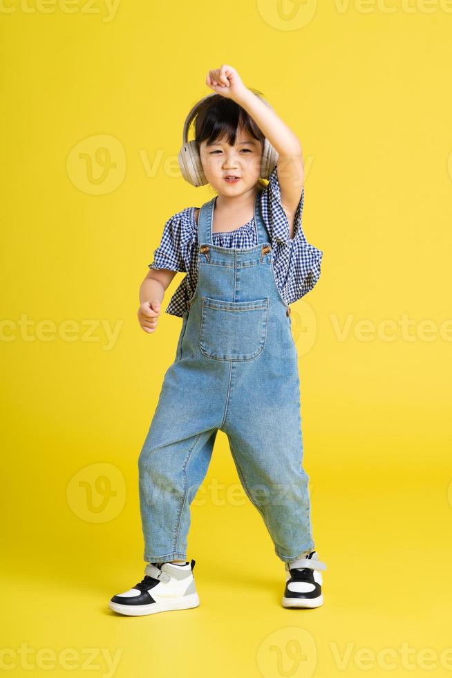 full body image of beautiful asian baby girl on yellow background photo