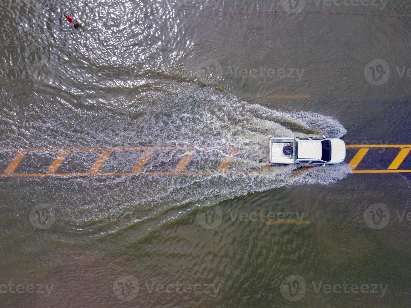 Flooded roads, people with cars running through. Aerial drone photography shows streets flooding and people's cars passing by, splashing water. photo
