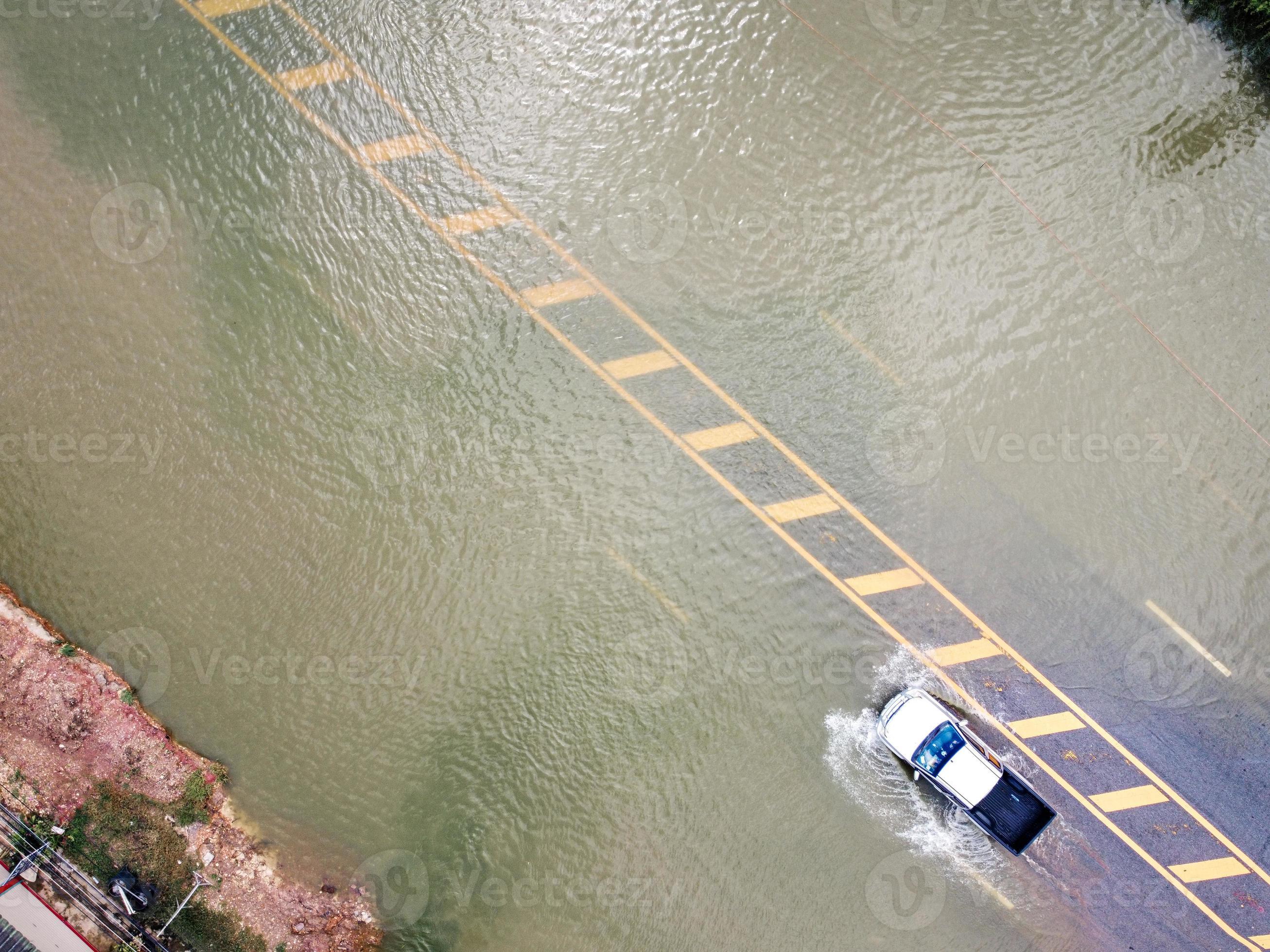 Flooded roads, people with cars running through. Aerial drone
