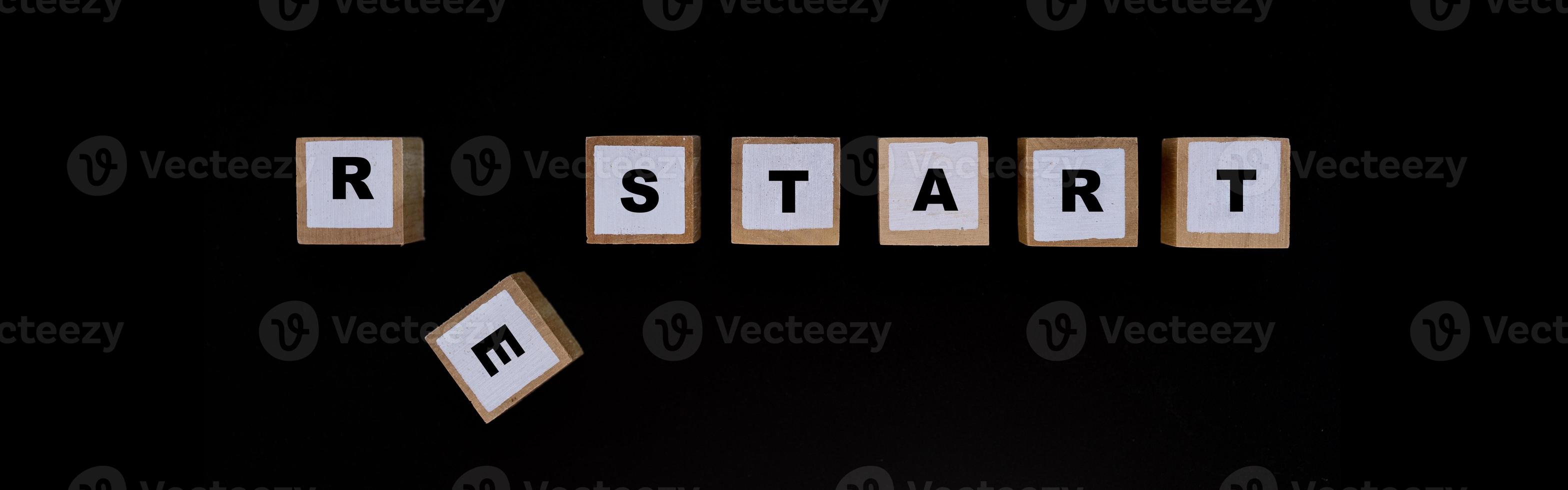 Concept of new beginnings, Square wooden blocks with RESTART text on a black background. photo