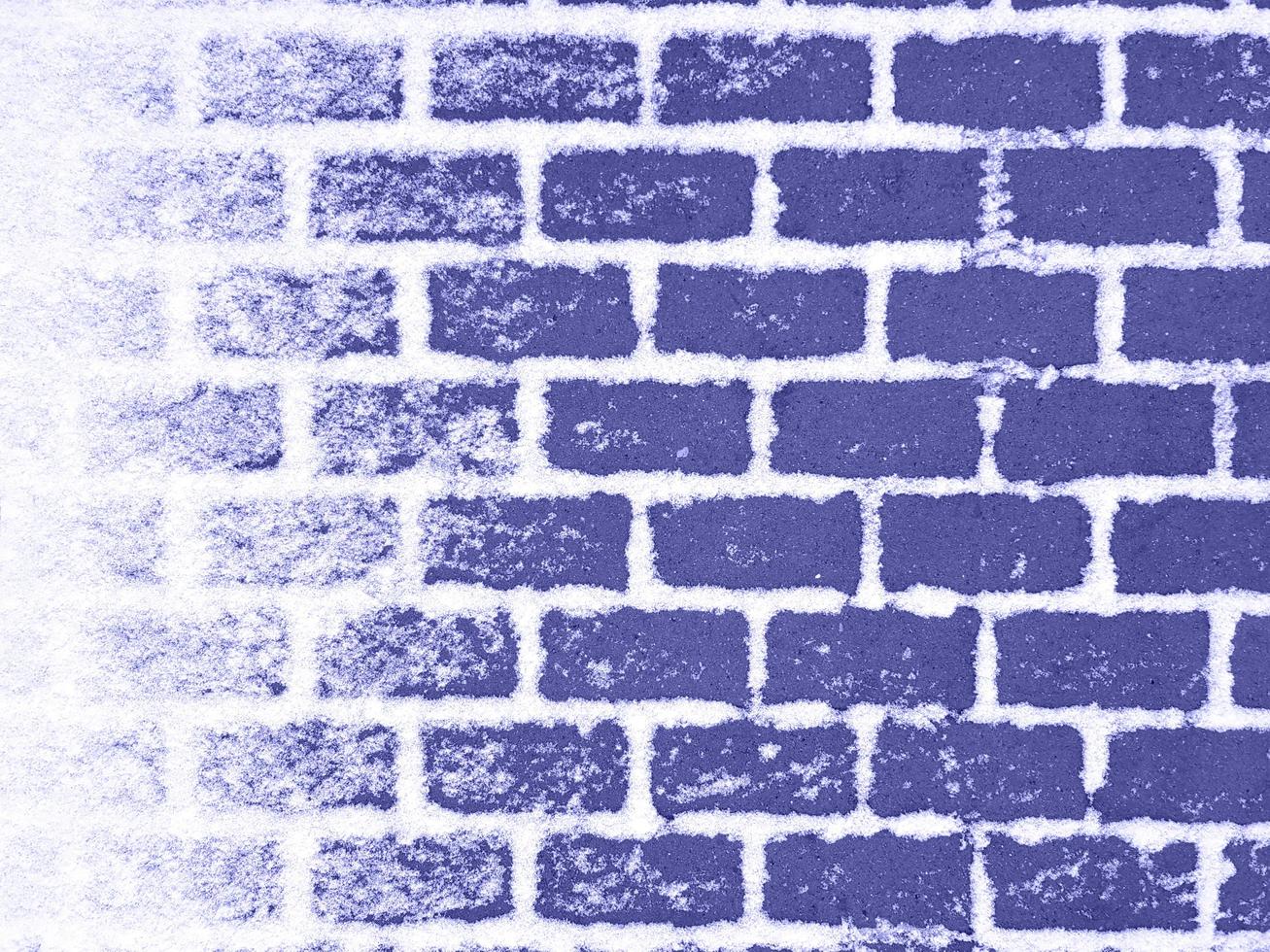 Inspired by trendy very peri color of the year 2022. Dark violet footpath paving stones with white snow in gaps between. The left side is covered with snow. Winter street background with copy space. photo