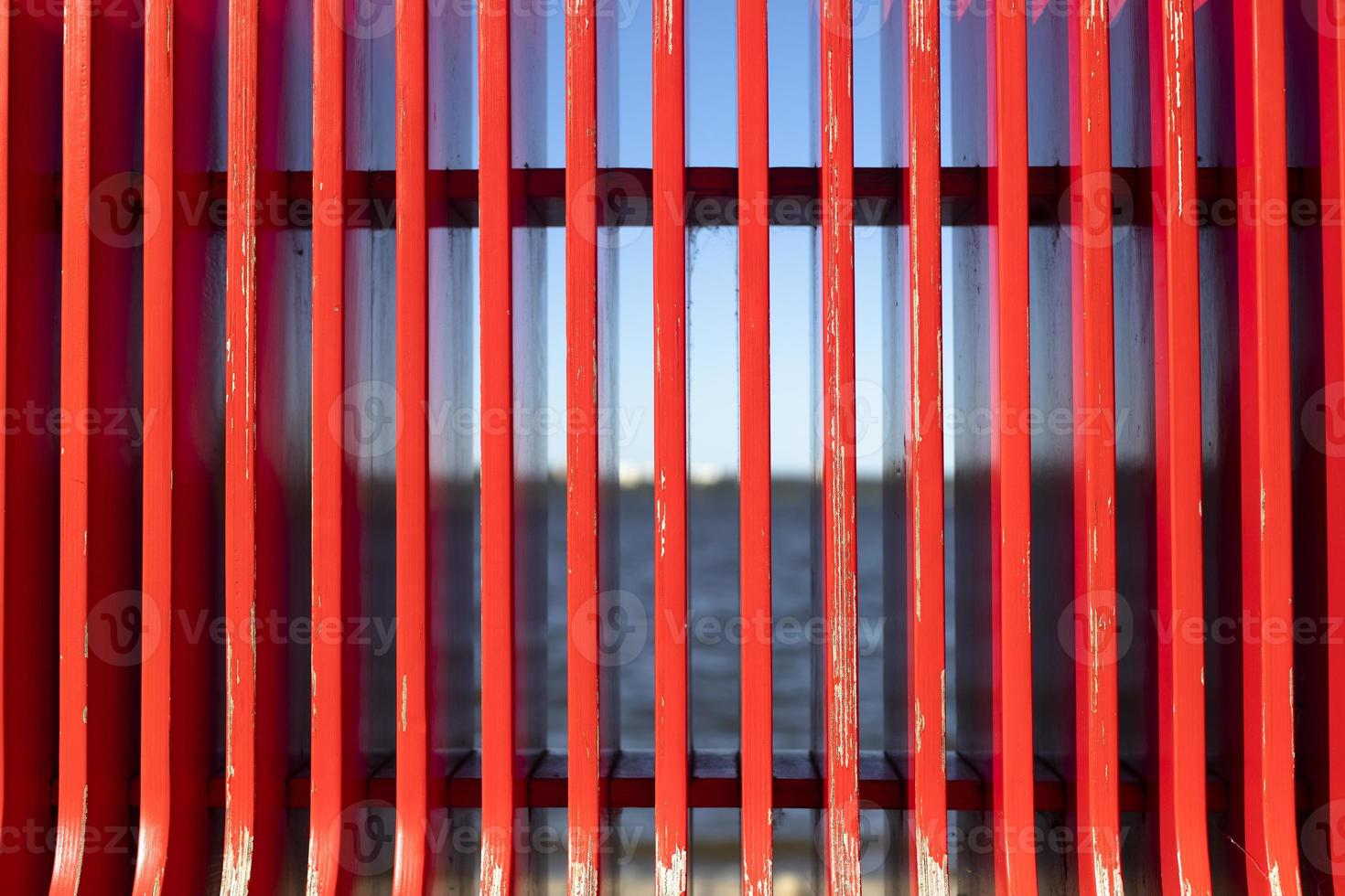 Red texture on background of sea. Details of bench on embankment. Red vertical lines. photo