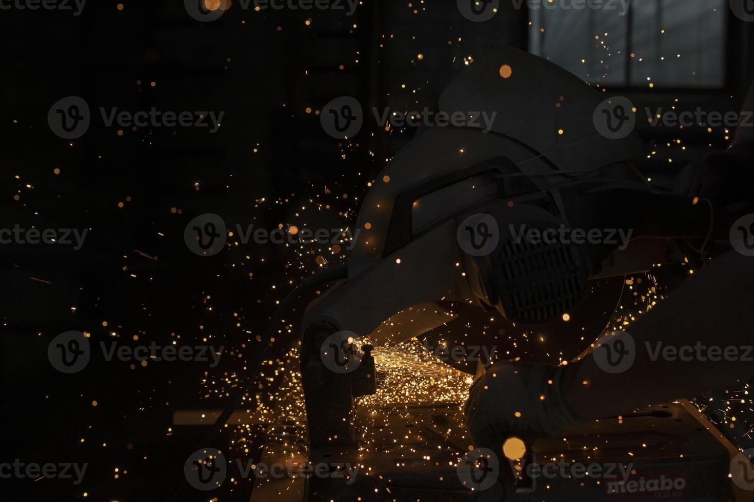 Sparks from grinder. Metal cutting. Bright lights in dark. Industrial background. photo