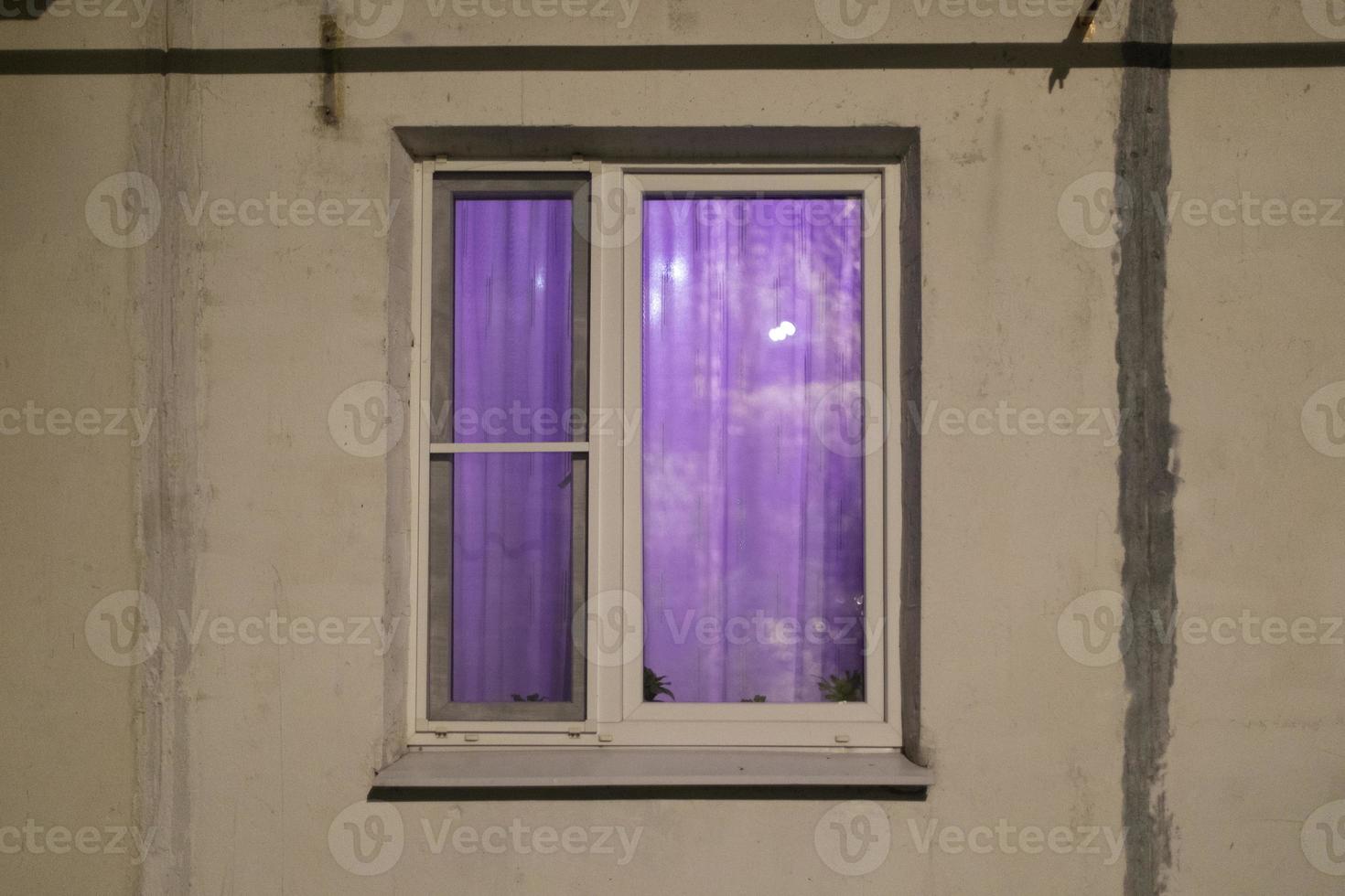 Window in building. Purple light in white window. Details of building. photo