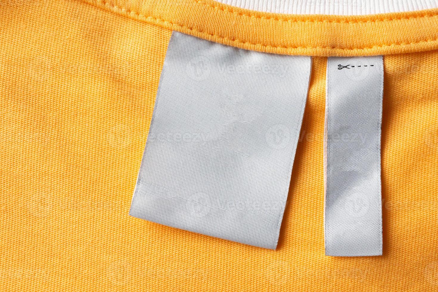 Blank white laundry care clothes label on yellow fabric texture background photo