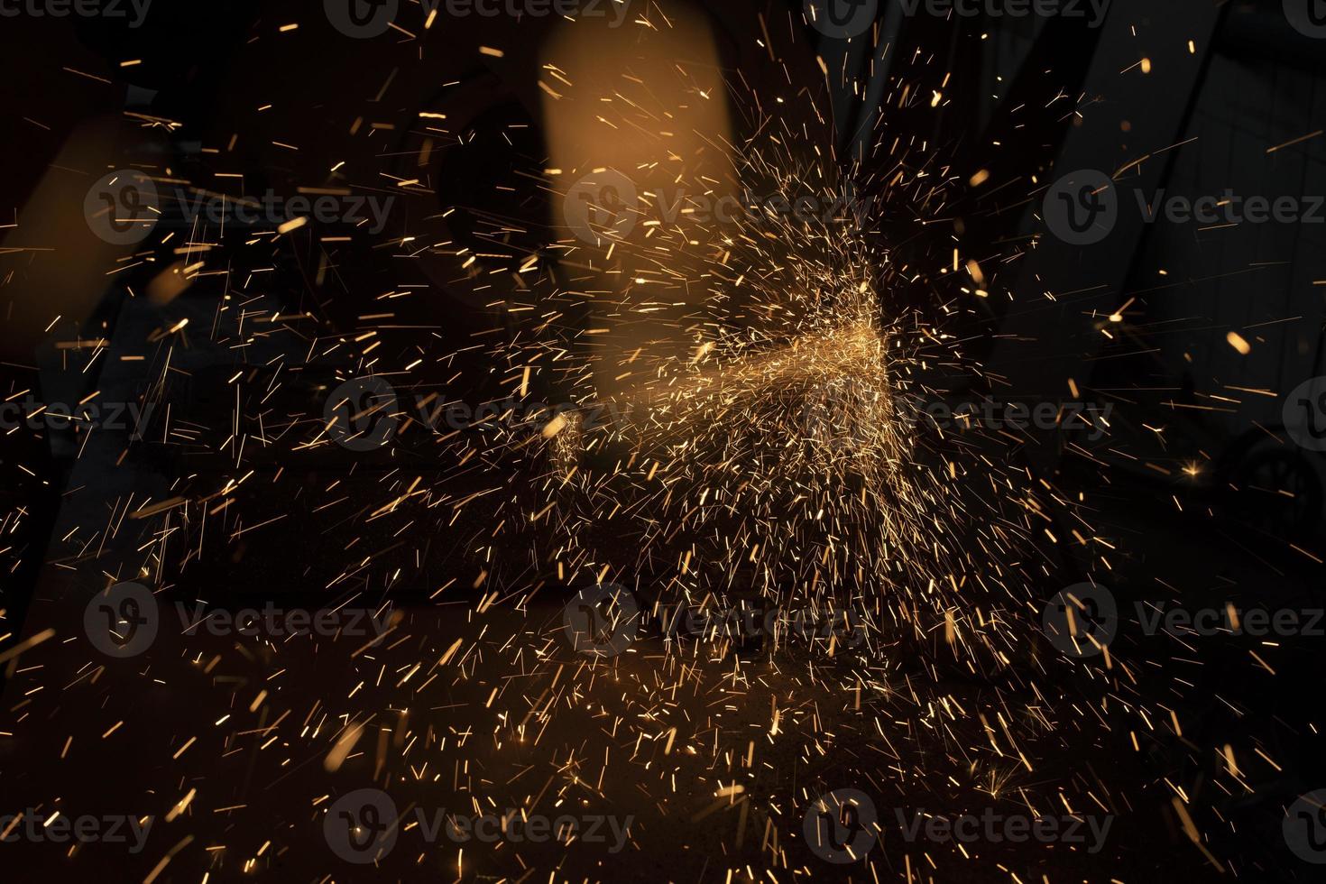Sparks from grinder. Metal cutting. Bright lights in dark. Industrial background. photo