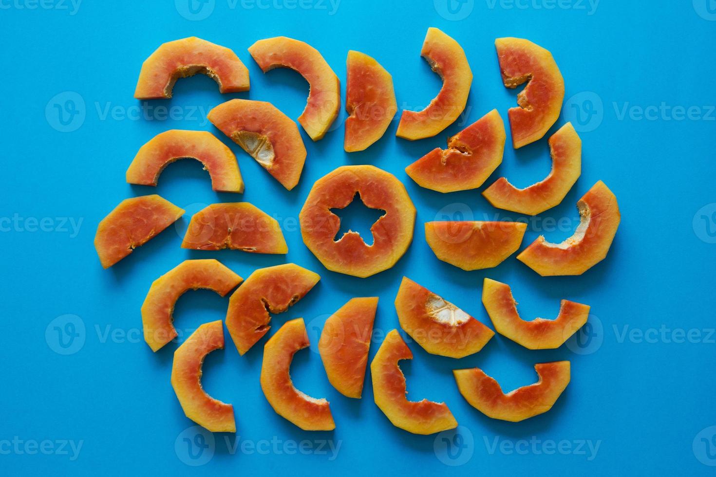 Pieces of orange papaya on blue background. photo