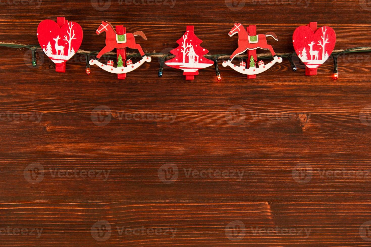 adornos navideños de madera roja y blanca y luces navideñas en el fondo de madera marrón, vista superior. foto