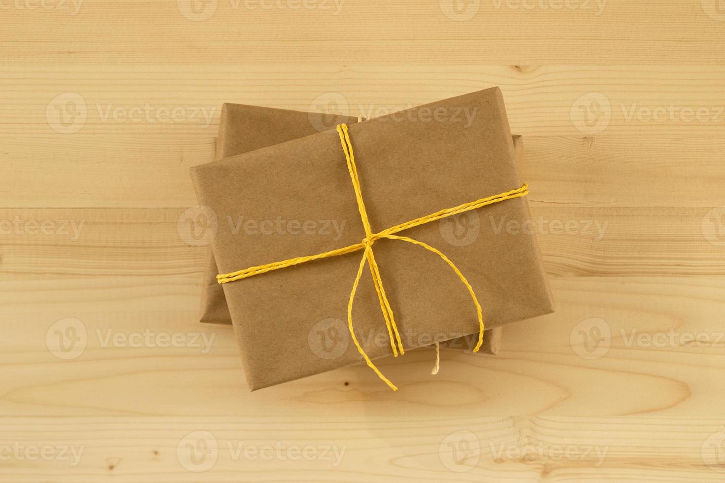 Two gift boxes wrapped of craft paper and yellow ribbon on the wooden background, top view. photo