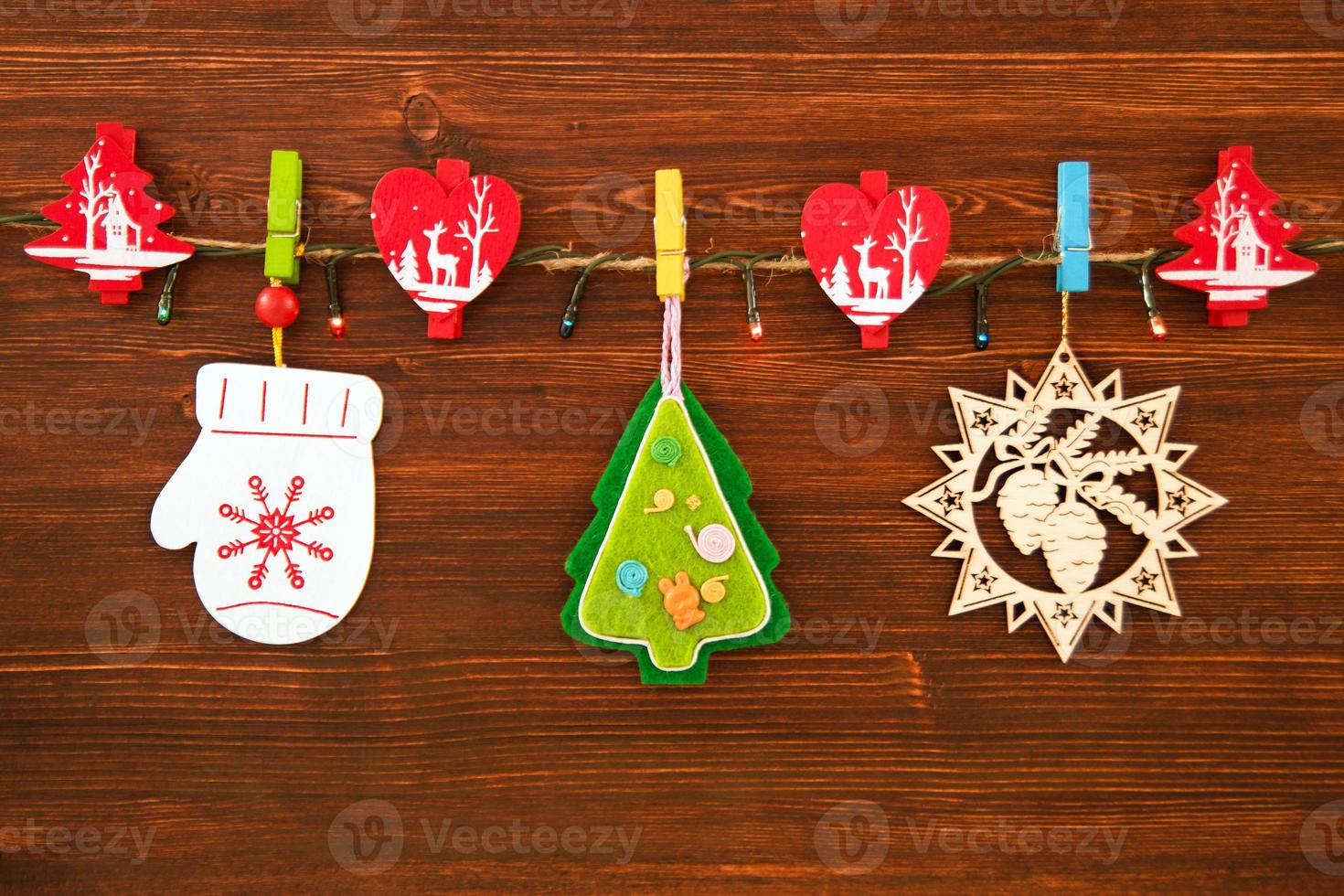 Wooden and felt Christmas decorations and Christmas lights on a rope on the brown wooden background, top view. photo