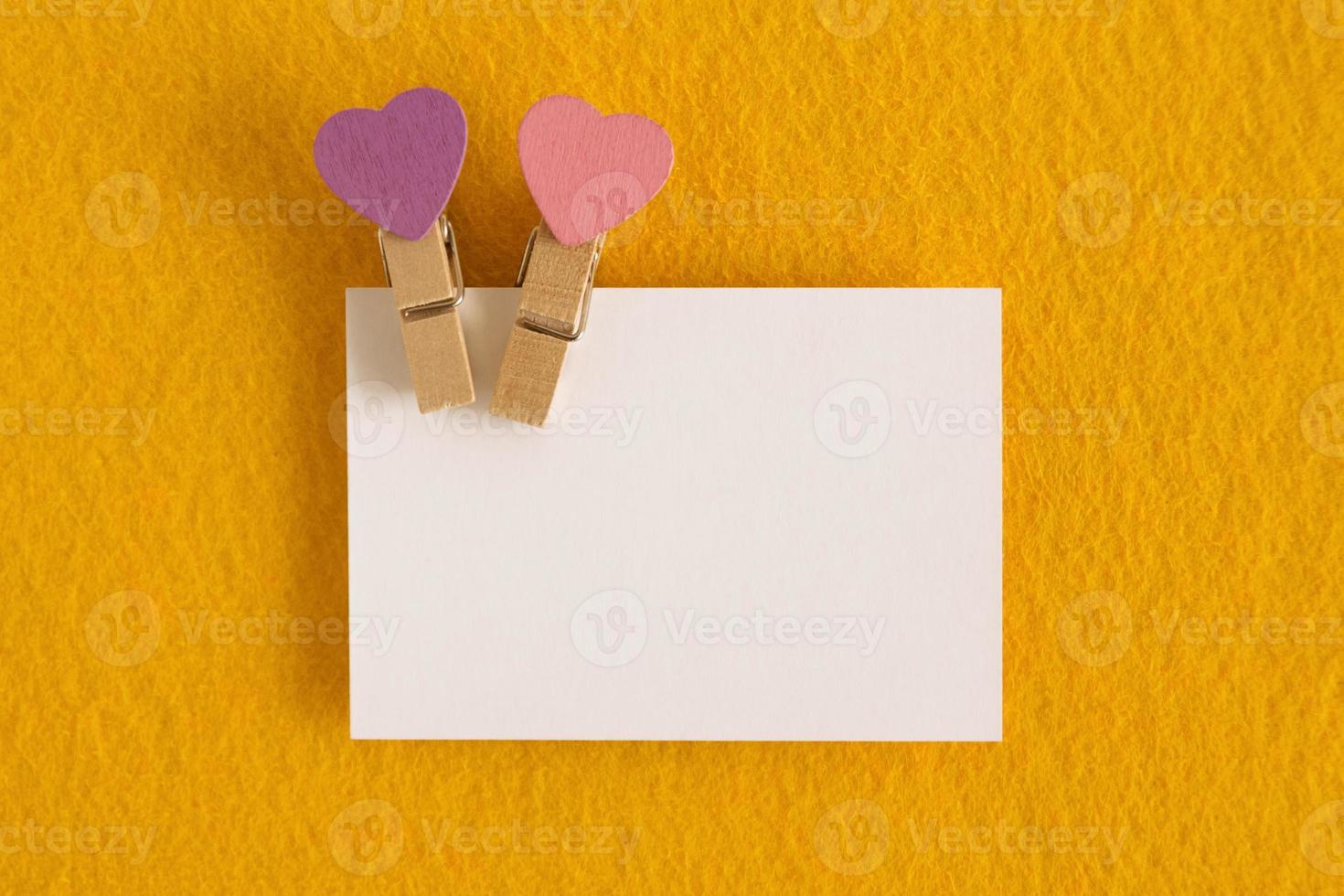 White sheet with pink and purple pins on the yellow background for Valentine Day. Copy space. photo