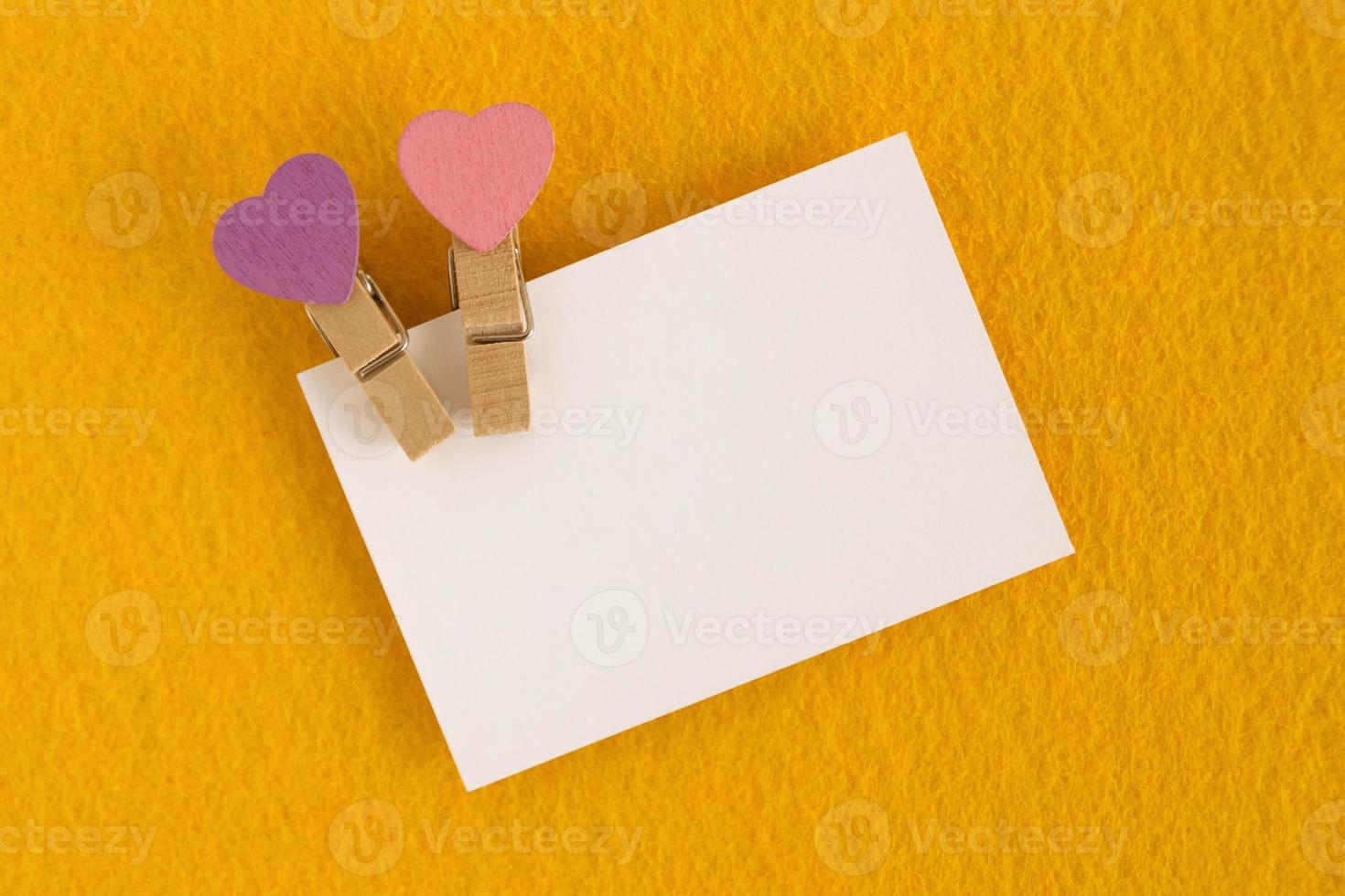 White sheet with pink and purple pins on the yellow background for Valentine Day. Copy space. photo
