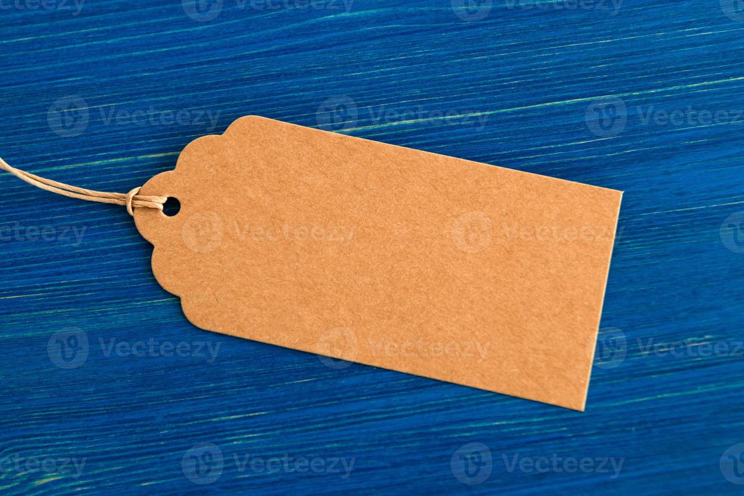 Brown blank paper price tag or label set on the blue wooden background, closeup. photo