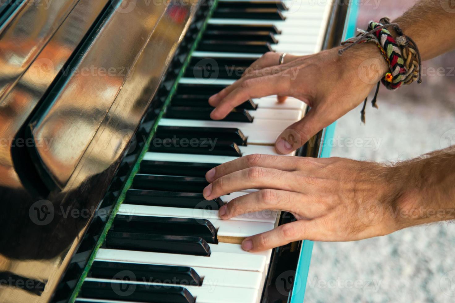 The hands of a young man playing piano on a street of city, closeup. photo