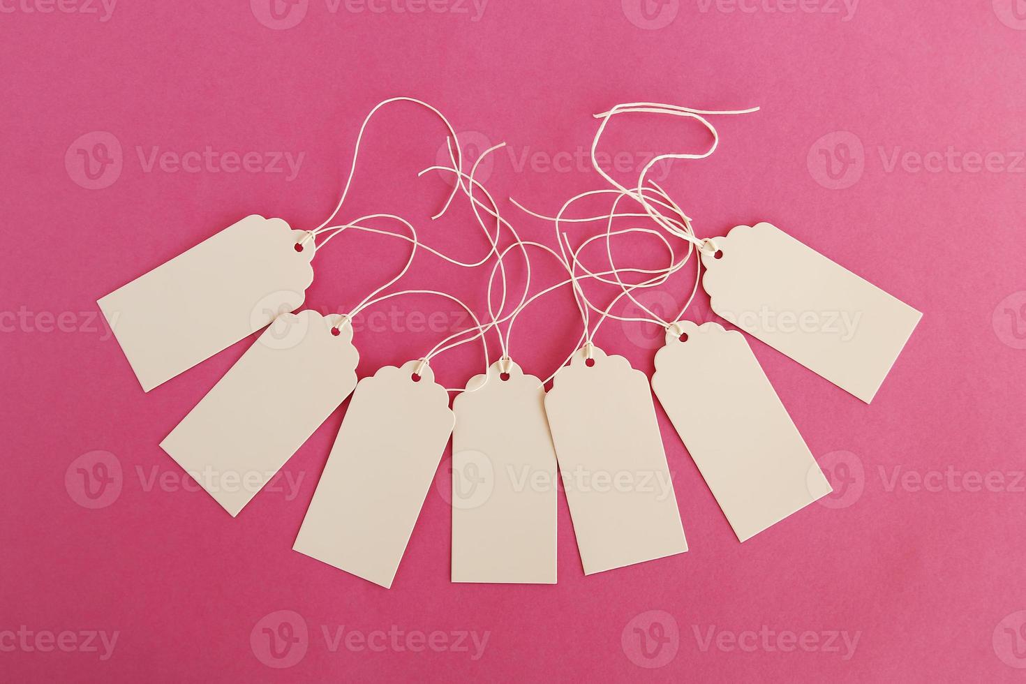 White blank paper price tags or labels set on the pink background, top view. photo