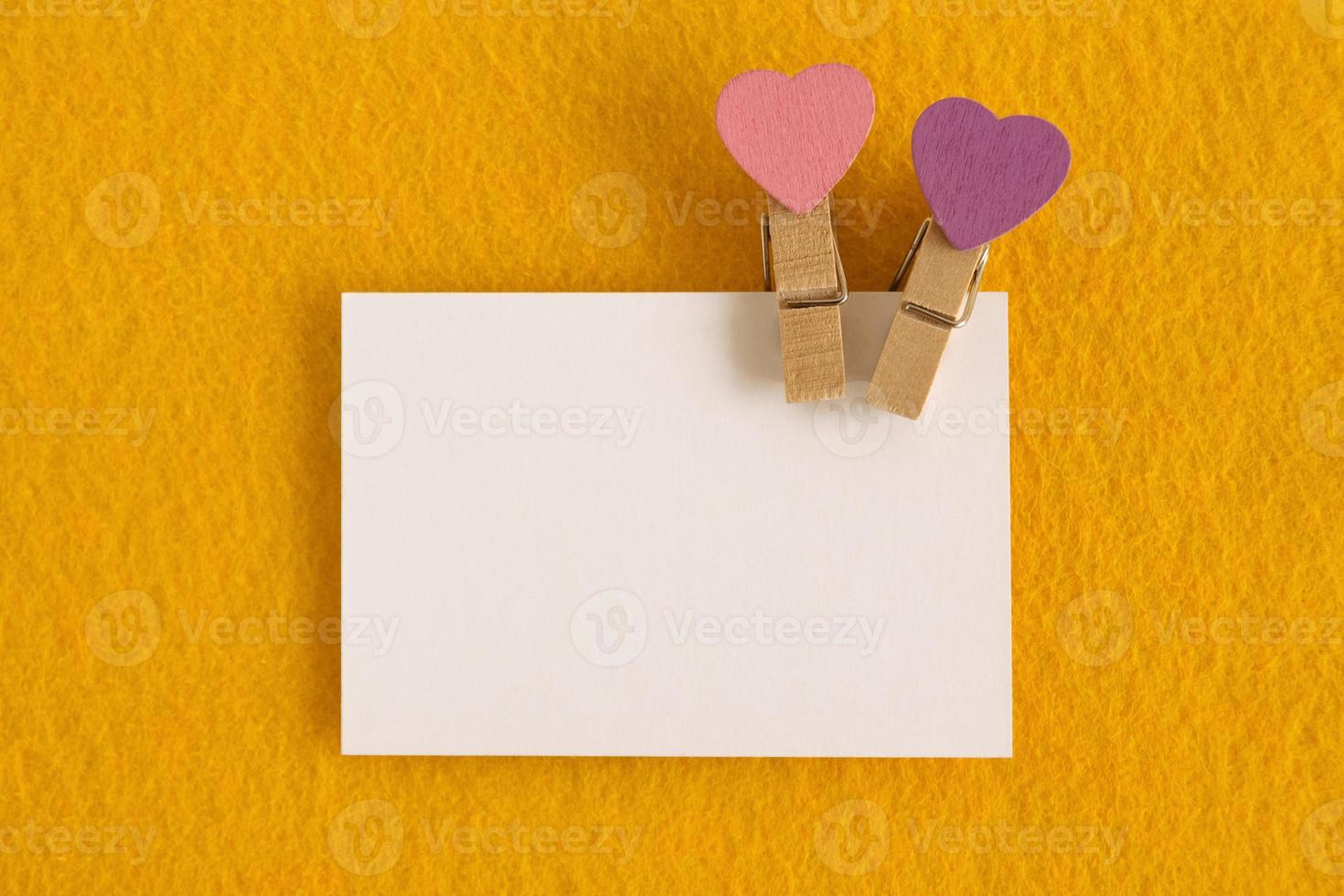 White sheet with pink and purple pins on the yellow background for Valentine Day. Copy space. photo