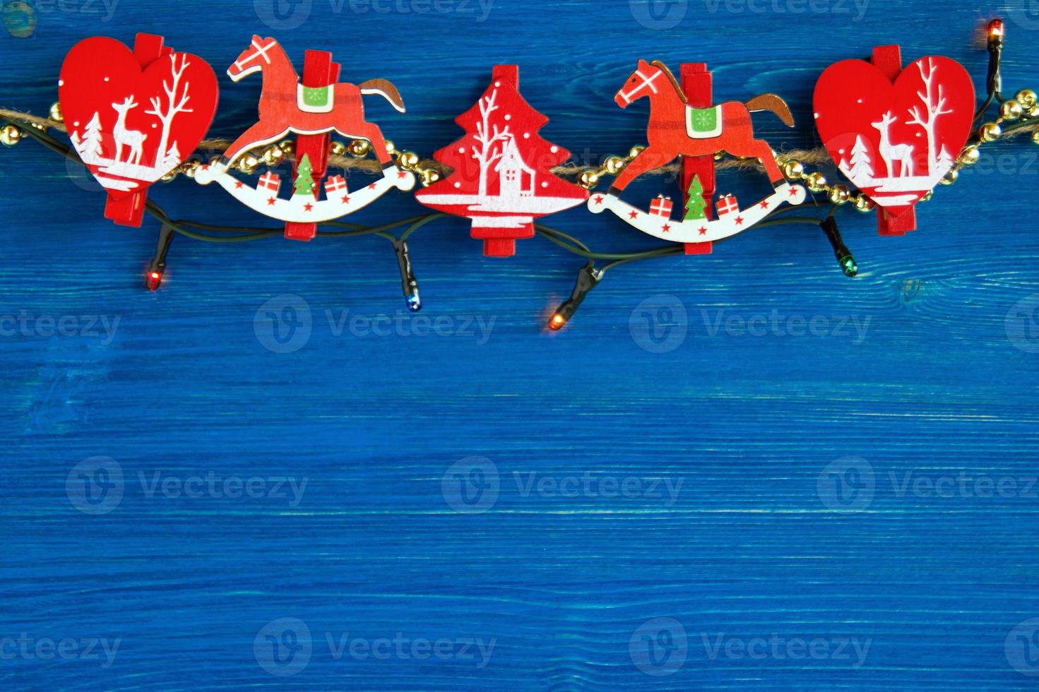 Red and white wooden Christmas decorations and Christmas lights on the blue wooden background, top view. photo