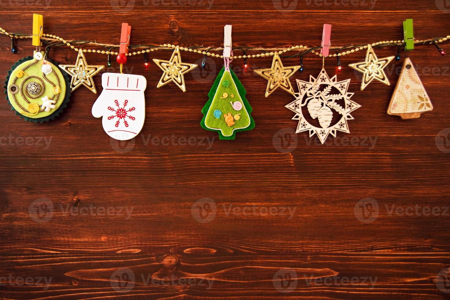 Wooden and felt Christmas decorations and Christmas lights on a rope on the brown wooden background, top view. photo