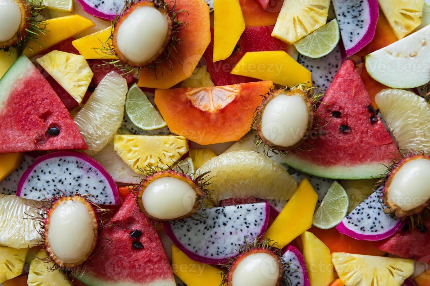 primer plano de frutas frescas mixtas para un fondo colorido. fruta del dragón, piña, papaya, lima, mango, pomelo, rambután, sandía. foto