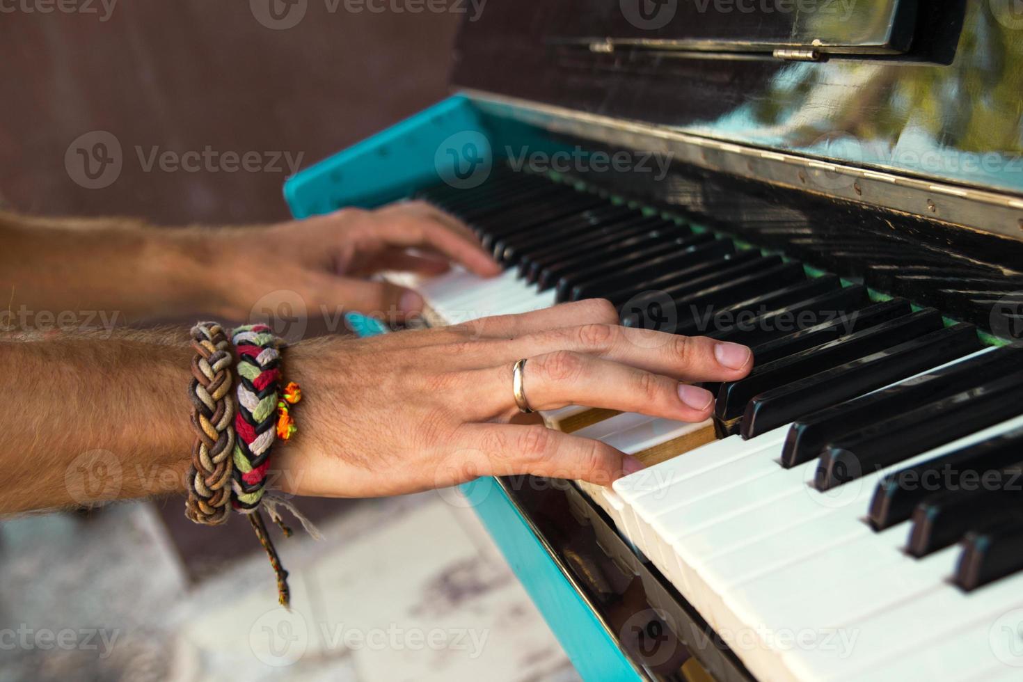 The hands of a young man playing piano on a street of city, closeup. photo