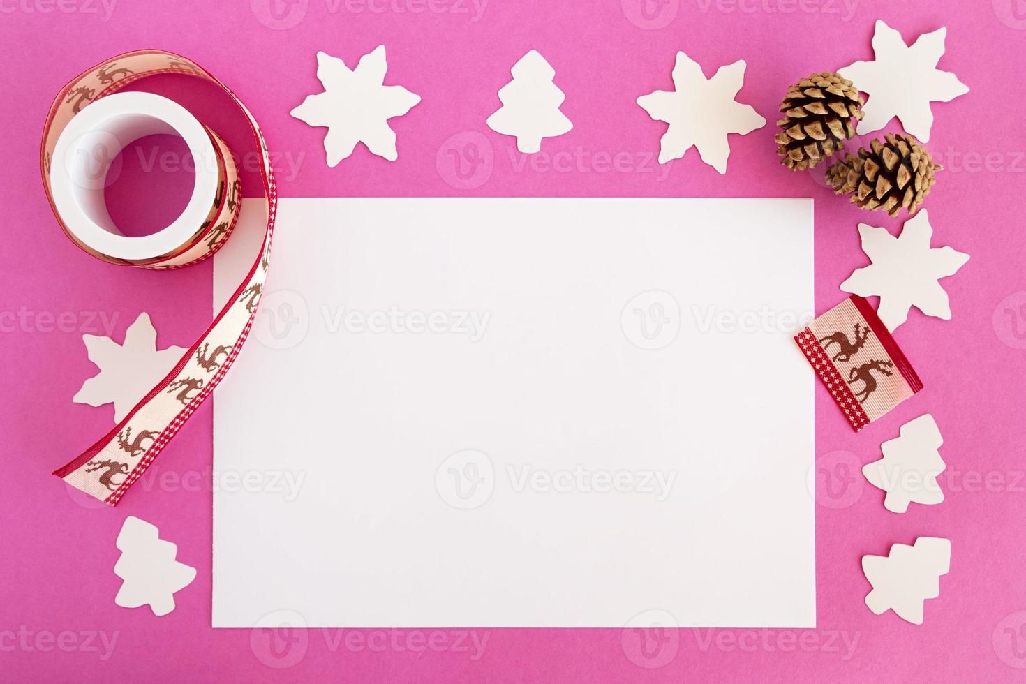 Top view on the Christmas decorations and white sheet of paper on the pink background with copy space. photo